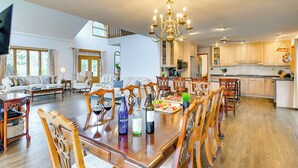 Un vaste salon comprenant un coin repas, une cuisine et un grand lustre.
