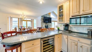 Une cuisine spacieuse dotée de plans de travail en granit, d’armoires en bois, d’un four encastré et d’un grand îlot central avec des places assises.