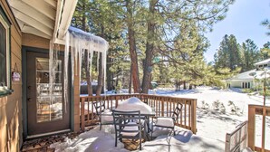 A wooden deck with a table and chairs covered in snow, surrounded by trees. - Pet-friendly Cabin in Pinetop-lakeside! (Pinetop)