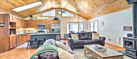 A spacious living area with a wooden ceiling, a leather sofa, a coffee table, and a fireplace.