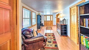 A spacious hallway with a leather sofa, a bookshelf, and a wooden door. - Pet-friendly Cabin in Pinetop-lakeside! (Pinetop)
