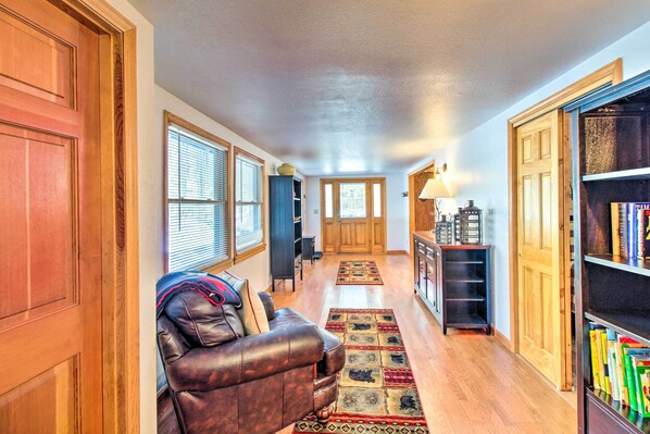 A spacious hallway with a leather sofa, a bookshelf, and a wooden door. - Pet-friendly Cabin in Pinetop-lakeside! (Pinetop)