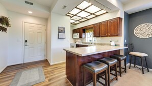 A kitchen with wooden cabinets, a marble countertop, and a built-in island with bar stools. - Family-friendly Branson Condo w/ Golf Course Views (Branson West)