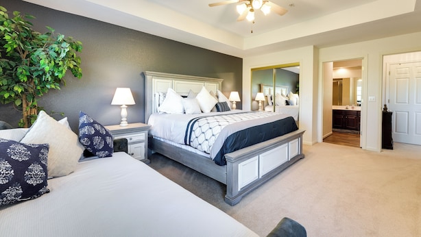 A bedroom with a bed, bedside tables, a ceiling fan, and a large mirror. - Family-friendly Branson Condo w/ Golf Course Views (Branson West)