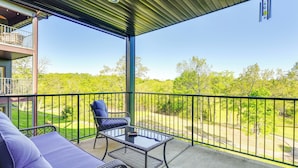 A balcony with a wicker sofa and a table, overlooking a green landscape. - Family-friendly Branson Condo w/ Golf Course Views (Branson West)