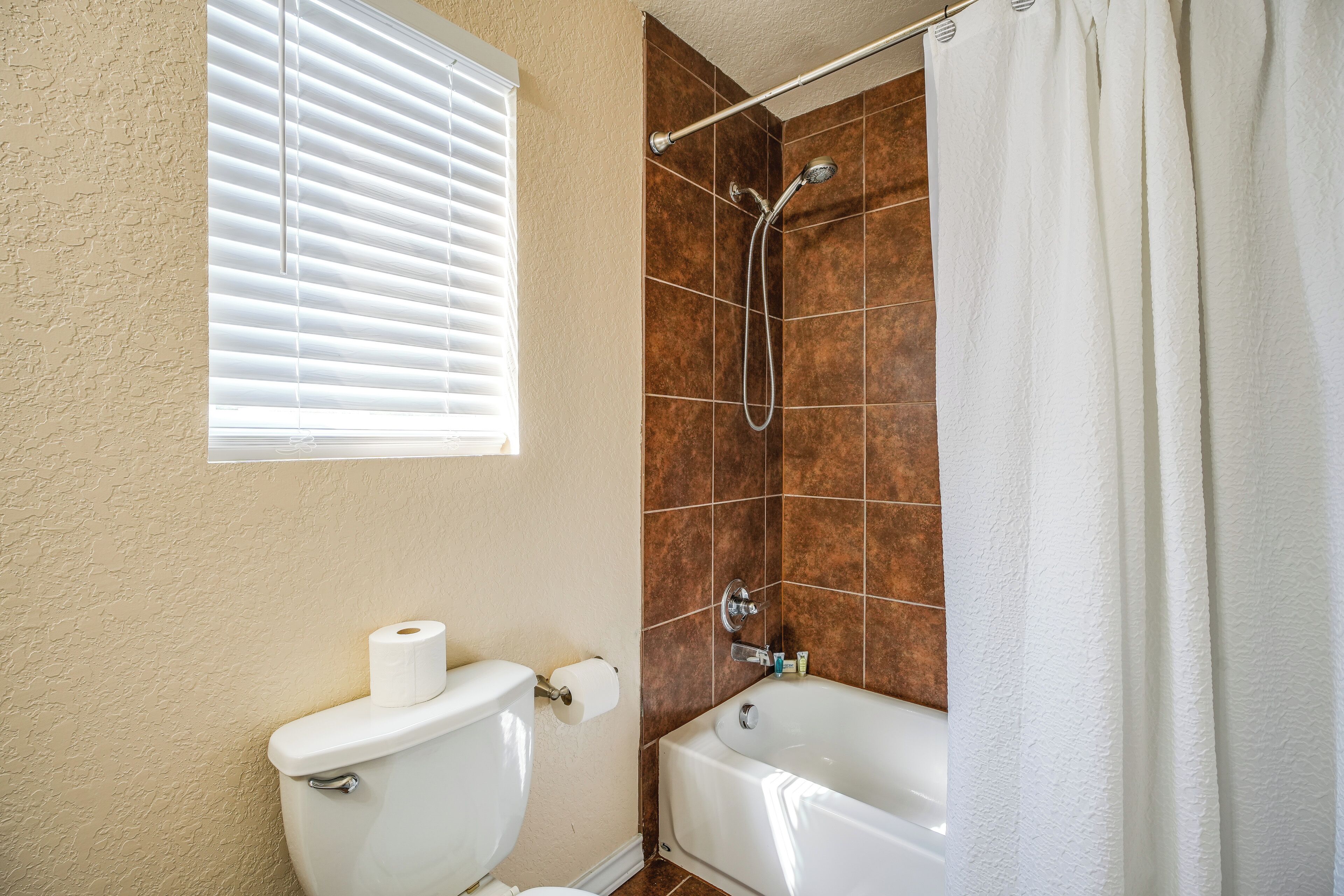 Un baño con inodoro, ducha con puerta de cristal y bañera.