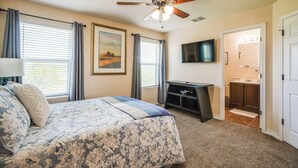 A bedroom with a bed, a ceiling fan, a TV, a desk, and a bathroom visible through an open door. - San Antonio Townhome ~ 2 Mi to Aquarium! (San Antonio)