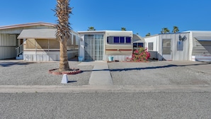 A row of RVs parked in a lot with a palm tree and a flower bed in the foreground. - Cozy Yuma Vacation Rental w/ Resort Amenities! (Yuma)