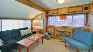 A cozy RV interior with a sofa, a blue chair, a table, and a bookshelf. - Cozy Yuma Vacation Rental w/ Resort Amenities! (Yuma)