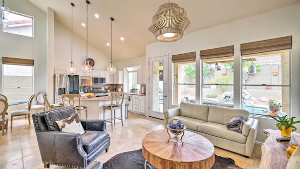 A spacious living area with a sofa, leather chairs, a coffee table, and a dining area with chairs and a table. - Golf & Unwind Poolside: Cave Creek Group Retreat! (Cave Creek)