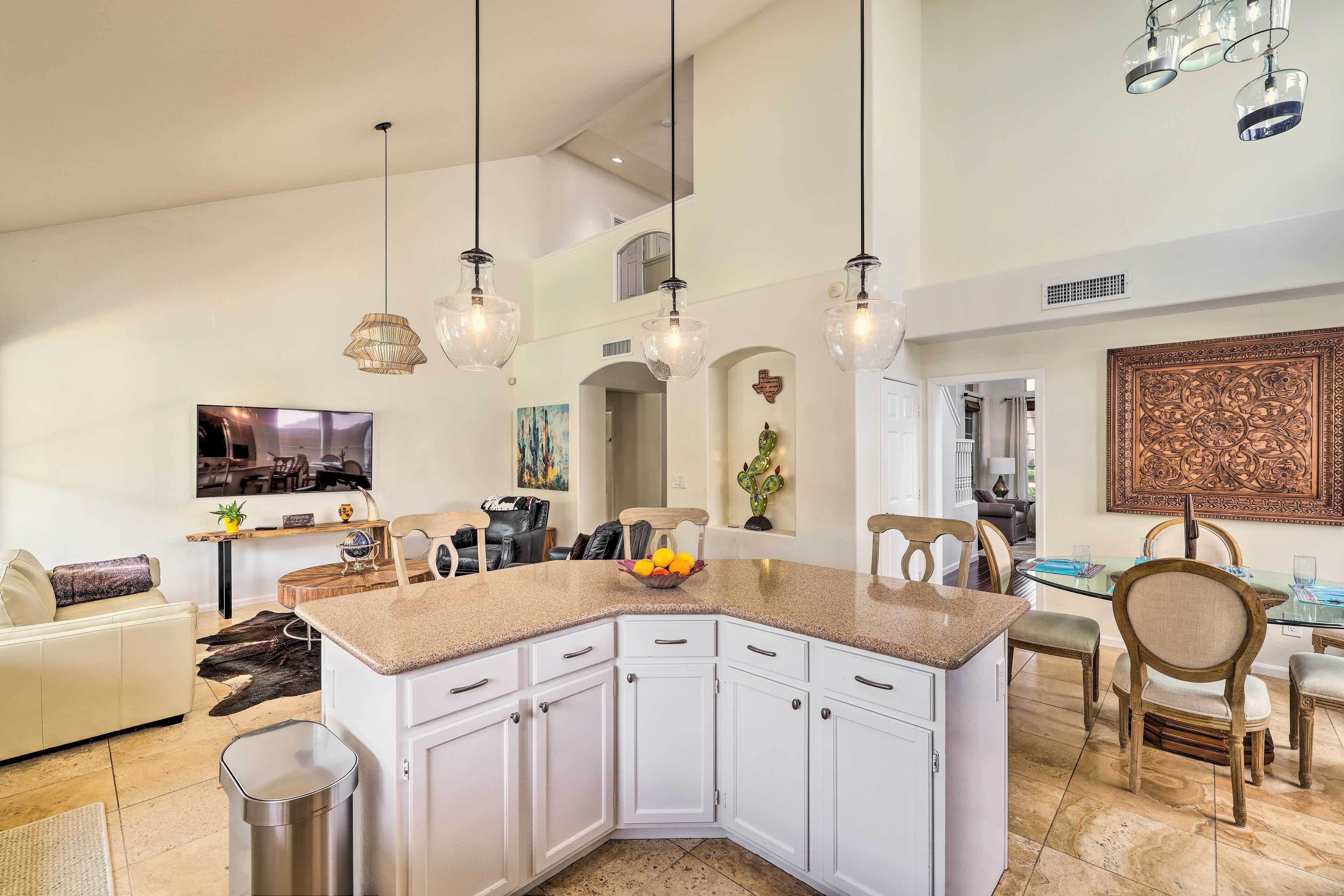 A modern kitchen with white cabinets, a granite countertop, and pendant lighting.