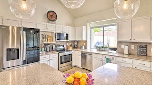 A modern kitchen with stainless steel appliances, white cabinets, and a granite countertop. - Golf & Unwind Poolside: Cave Creek Group Retreat! (Cave Creek)