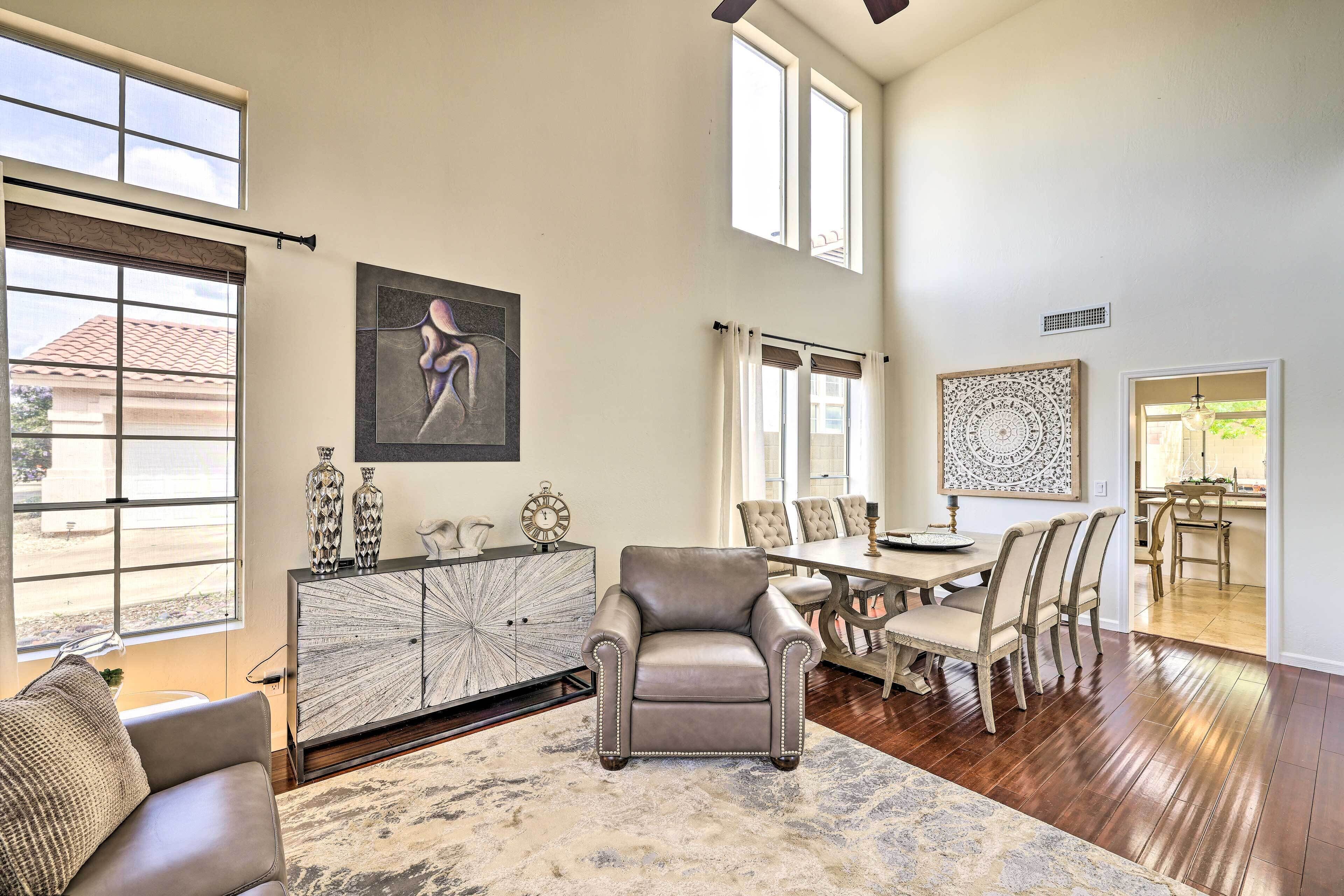 A spacious living room with a large window, a dining area with a table and chairs, and a modern fireplace.