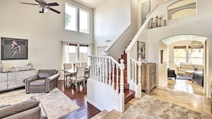 A spacious living area with a staircase, leather furniture, and a chandelier. - Golf & Unwind Poolside: Cave Creek Group Retreat! (Cave Creek)