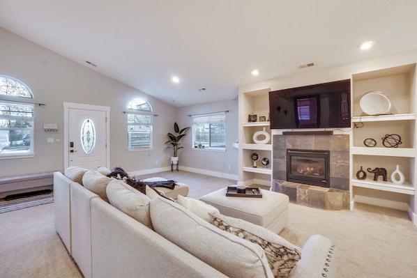 A spacious living room with a fireplace, white sofas, and a large window with a view. - Near Red Rocks: Golden Getaway w/ Deck! (Golden)