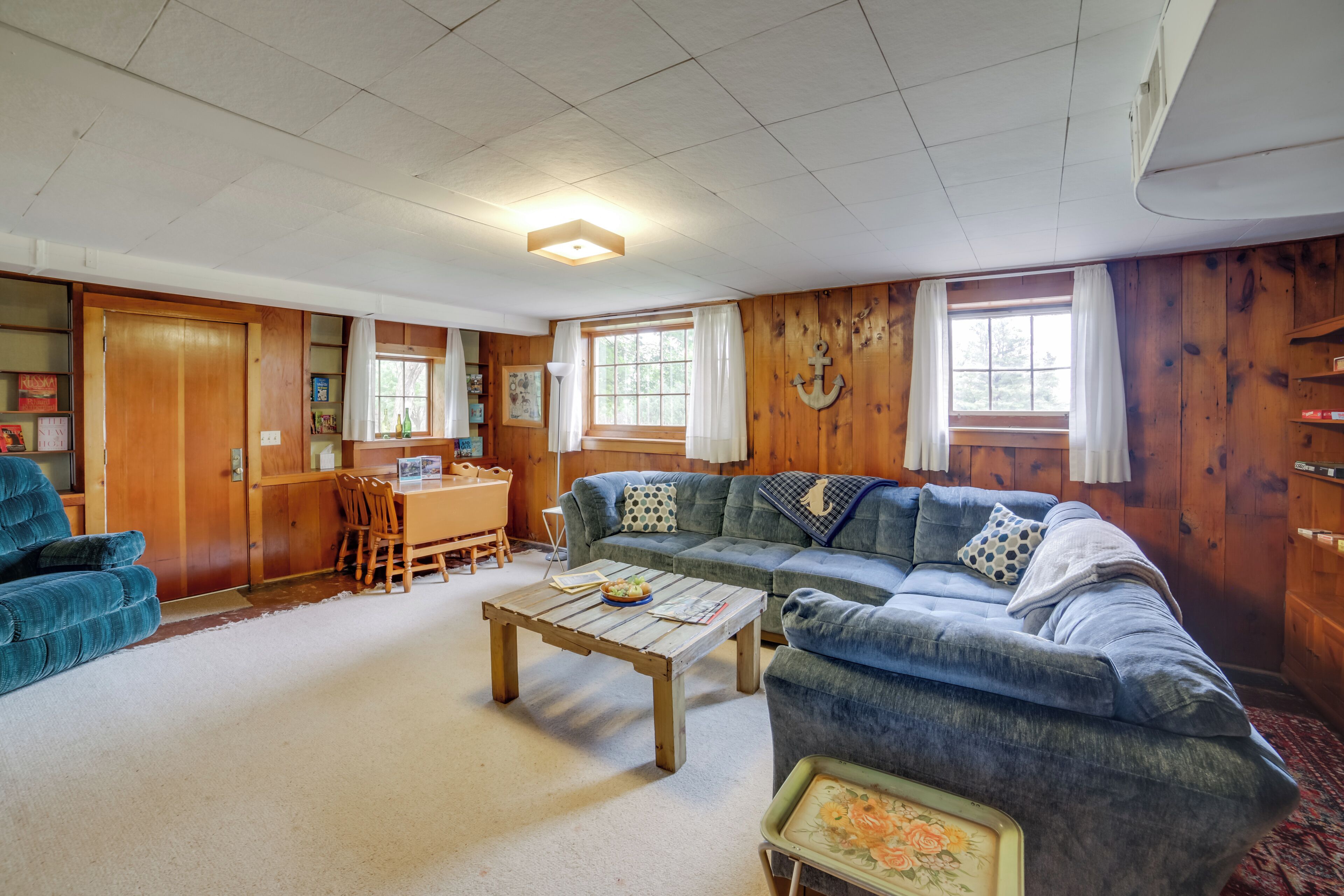 A cozy living room with a wooden floor, a blue sofa, a wooden coffee table, and a dining area with a table and chairs.