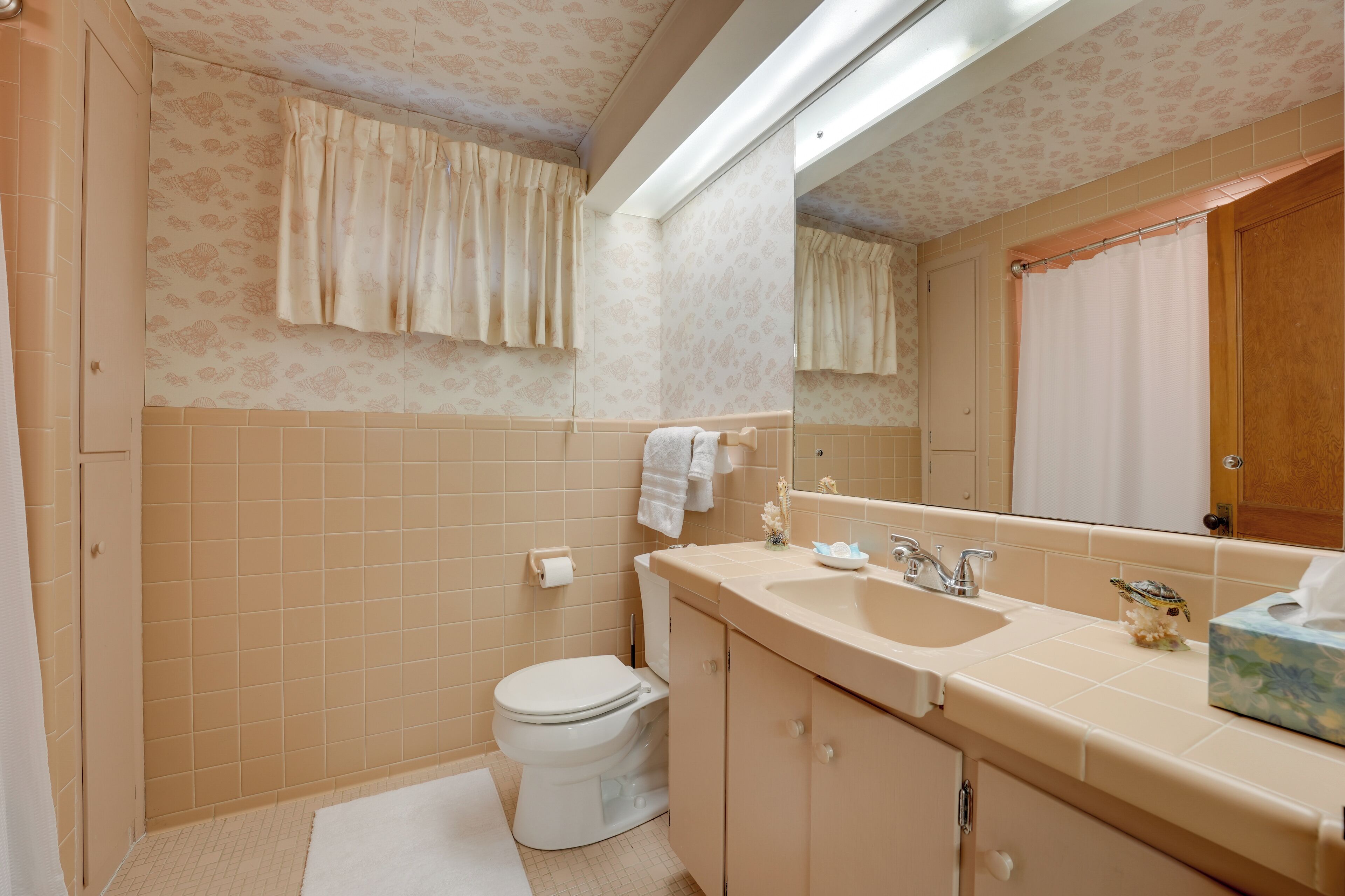 A bathroom with a toilet, sink, and mirror.