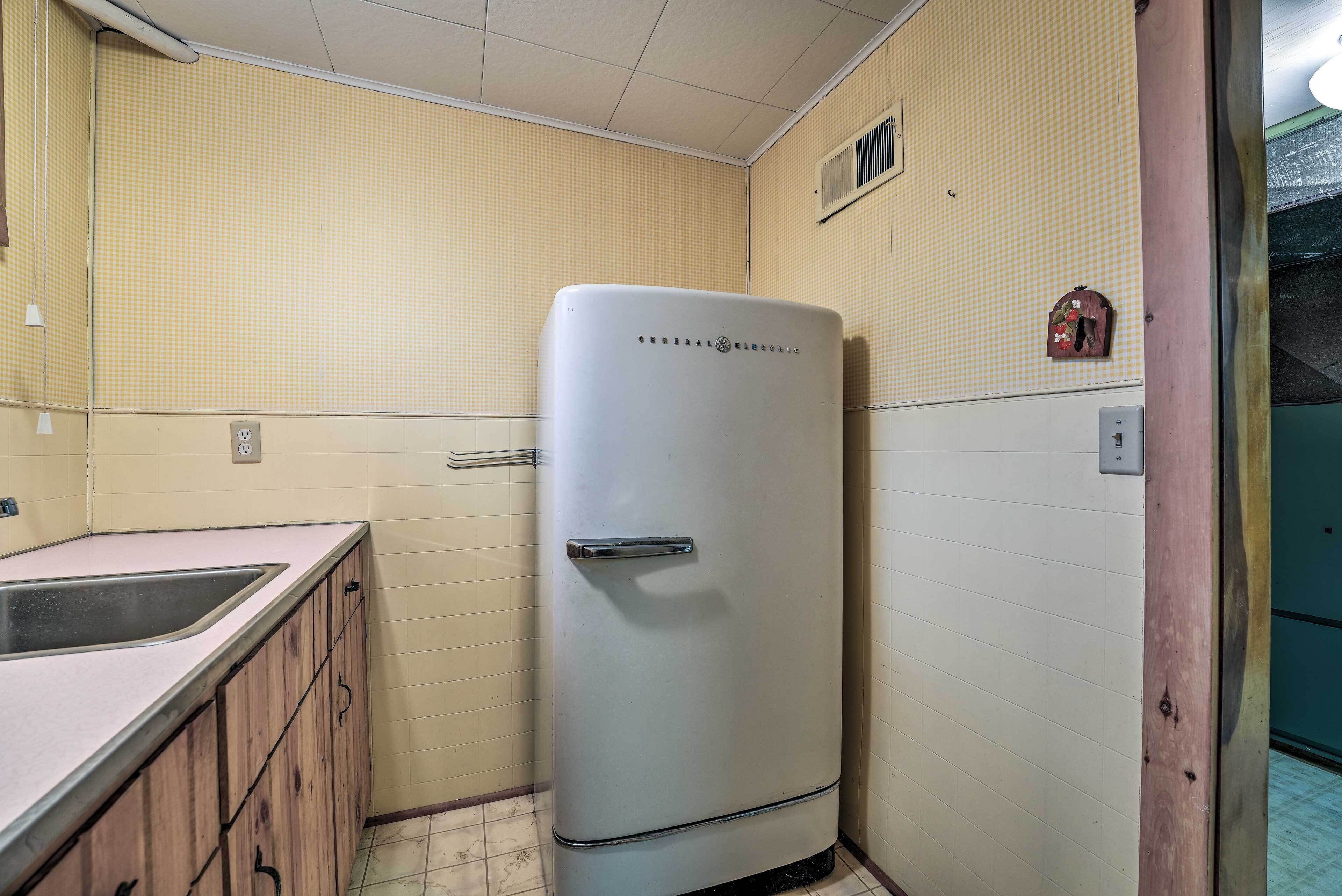 A compact kitchen with a sink, wooden cabinets, and a white refrigerator.