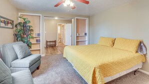 A bedroom with a bed, a chair, a ceiling fan, a bookshelf, and a door leading to another room. - Charming Gadsden Home w/ Golf Course Views! (Gadsden)