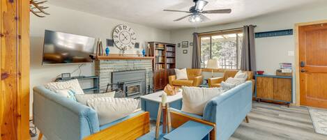 A cozy living room with a fireplace, a television, and a large clock on the wall.