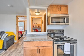 A compact kitchen with wooden cabinets, a built-in microwave, and a stove. - Waterfront Castle Rock Lake Cabin w/ Deck & Grill (Arkdale)