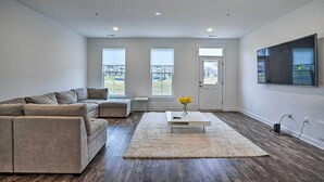 A modern living room with a sectional sofa, a coffee table, and a large TV on the wall. - Modern Townhome 4 Mi to Downtown Frederick! (Frederick)