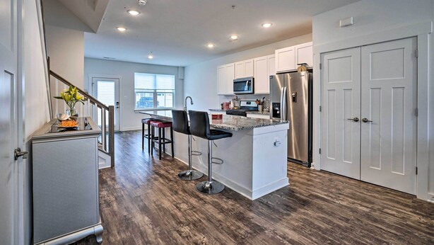 A modern kitchen with white cabinets, stainless steel appliances, and a central island with bar stools. - Modern Townhome 4 Mi to Downtown Frederick! (Frederick)