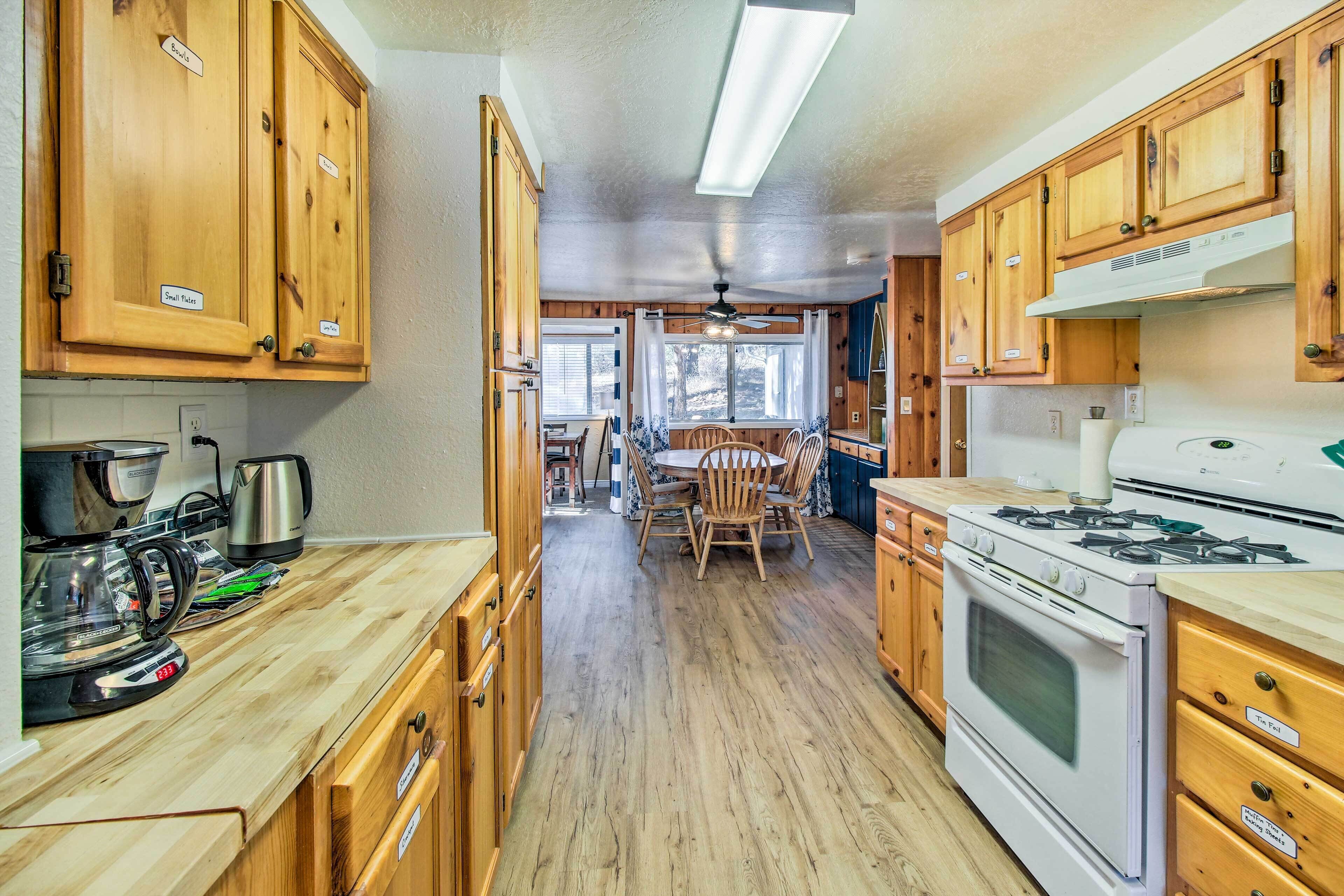 A kitchen with wooden cabinets, a stove, and a dining area with chairs and a table.