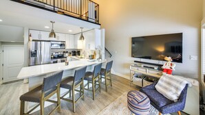 Una cocina moderna con una isla central, electrodomésticos de acero inoxidable y una zona de comedor con taburetes de bar.