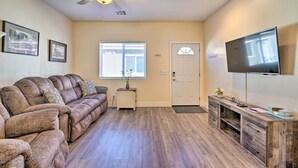 A living room with a sofa, a TV, a ceiling fan, and a door. - Pahrump Vacation Rental Apartment! (Pahrump)