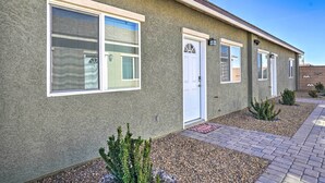 A single-story building with a stucco exterior, a front door, and a small garden area with gravel and plants. - Pahrump Vacation Rental Apartment! (Pahrump)