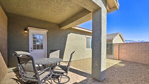 A patio with a table and chairs, a door, and a view of a mountain range. - Pahrump Vacation Rental Apartment! (Pahrump)