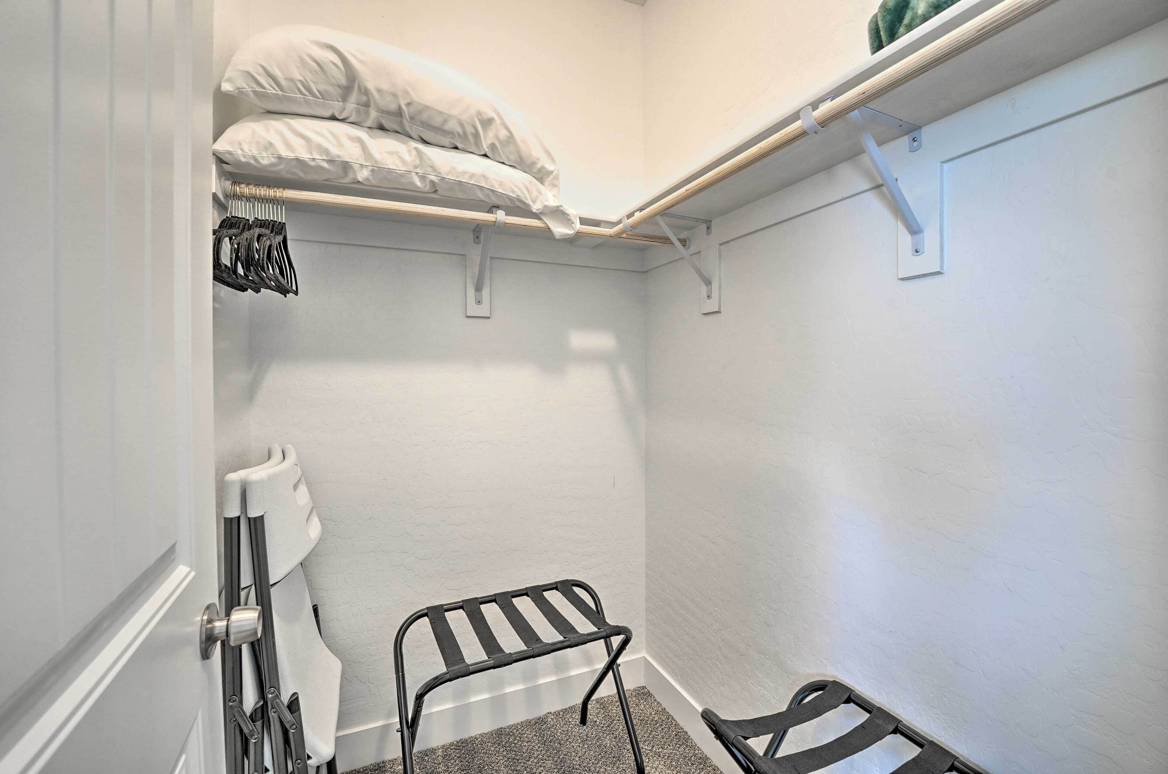A small, narrow room with a bunk bed, a metal chair, and a coat rack.