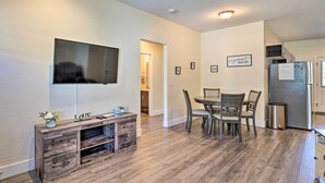 A modern kitchen with a dining area, wooden flooring, a flat-screen TV, and a refrigerator with a note. - Pahrump Vacation Rental Apartment! (Pahrump)