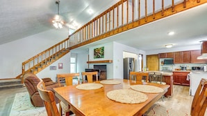 A spacious dining area with a wooden table and chairs, a staircase, and a kitchen in the background. - Cozy Lake Chatuge Getaway, Walk to Water! (Hayesville)