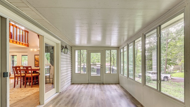 A covered porch with a wooden floor, large windows, and a door leading to an interior dining area. - Cozy Lake Chatuge Getaway, Walk to Water! (Hayesville)