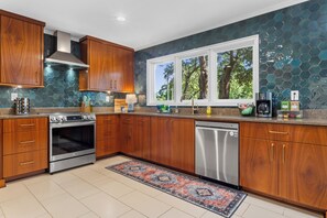 A modern kitchen with wooden cabinets, a stainless steel oven, and a dishwasher. - Live Oaks & Marina Views! Ocean Springs Home (Ocean Springs)