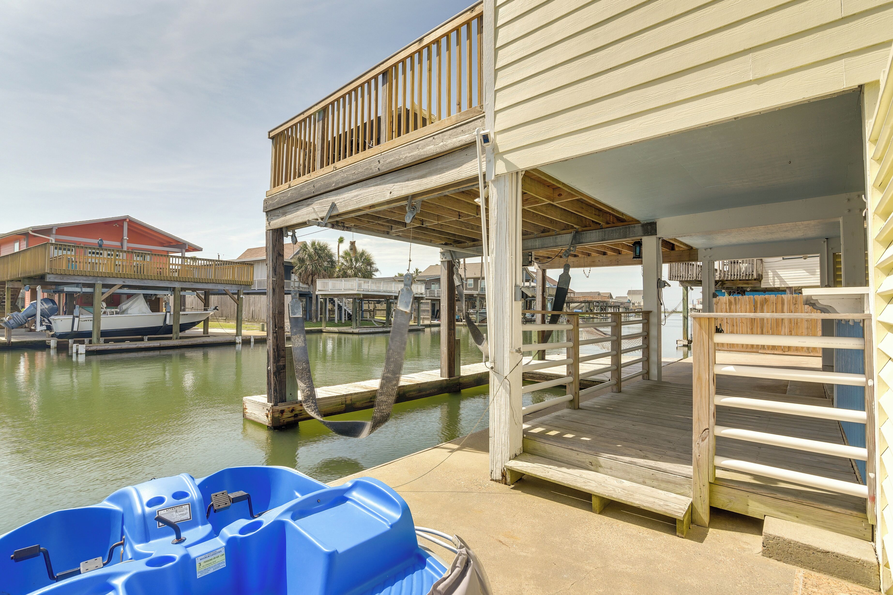 A waterfront property with a wooden deck, a covered area, and a boat dock.