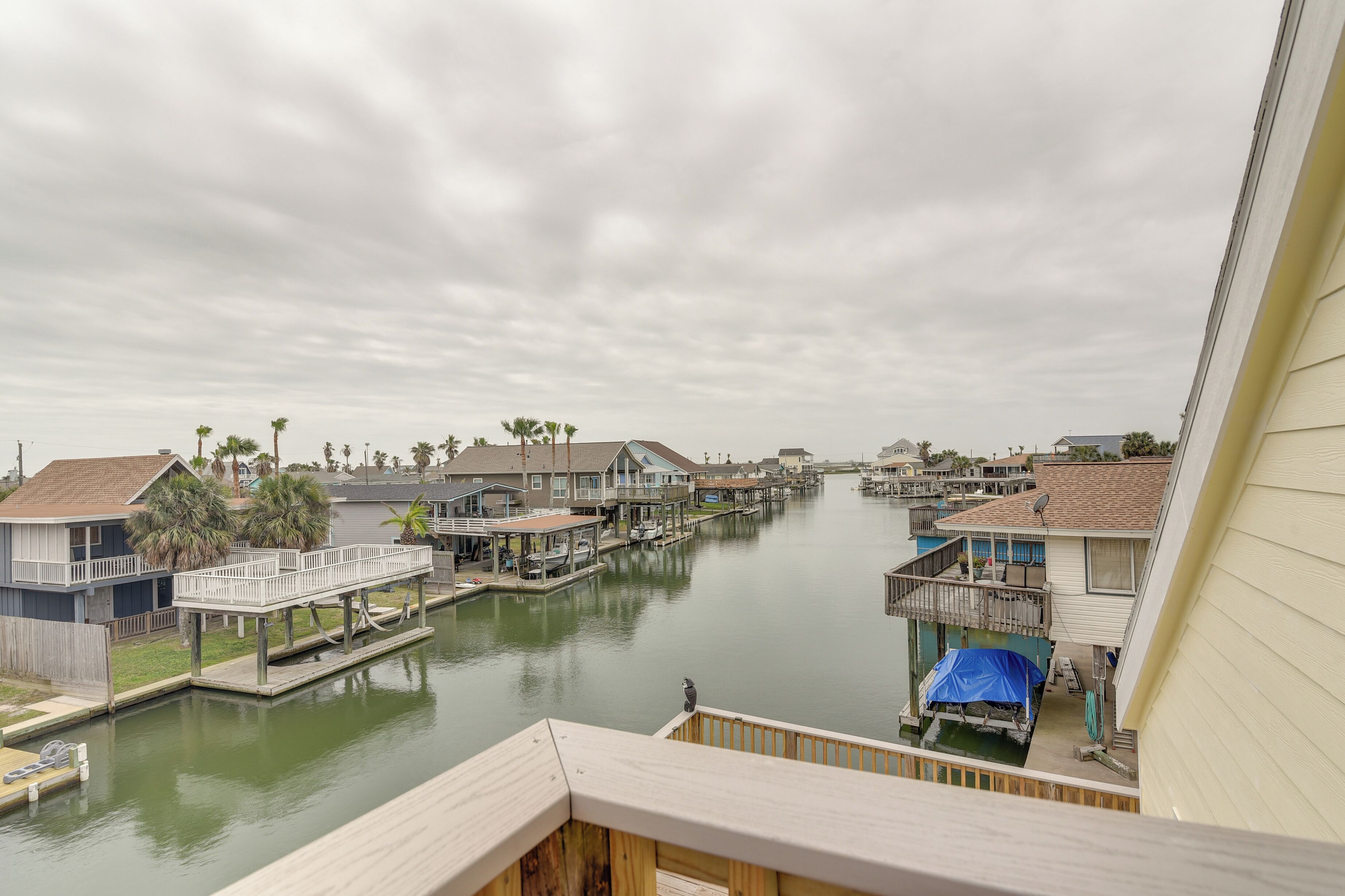 A canal with docked boats, waterfront houses, and a wooden deck overlooking the water.