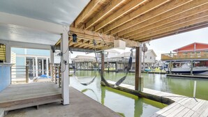 Eine überdachte Holzterrasse mit Betonboden, mit Blick auf ein Gewässer und Boote.