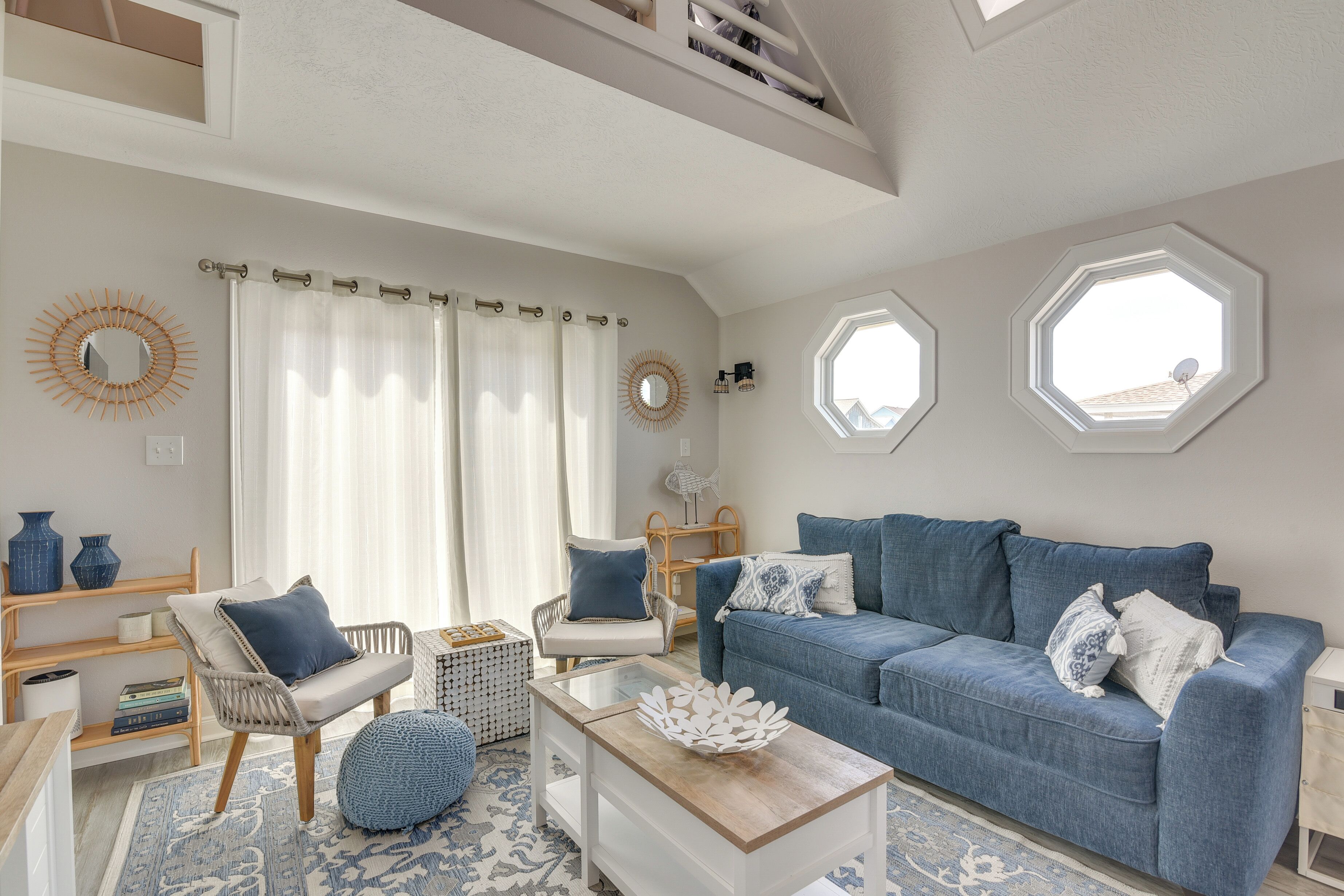 A living room with a blue sofa, white armchairs, a coffee table, and a patterned rug.