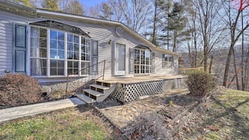 A single-story house with a front porch, a small set of stairs leading to the entrance, and a wooden deck.