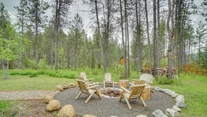 Un espace de détente circulaire, avec des fauteuils Adirondack disposés autour d’un foyer, le tout entouré de rochers et adossé à une forêt.