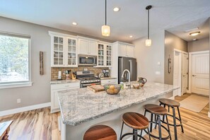 Una cocina moderna con encimeras de granito, electrodomésticos de acero inoxidable y una isla grande con taburetes de bar.