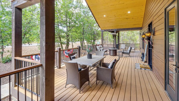 Una terraza de madera con una mesa y sillas, rodeada de puertas y ventanas de vidrio.