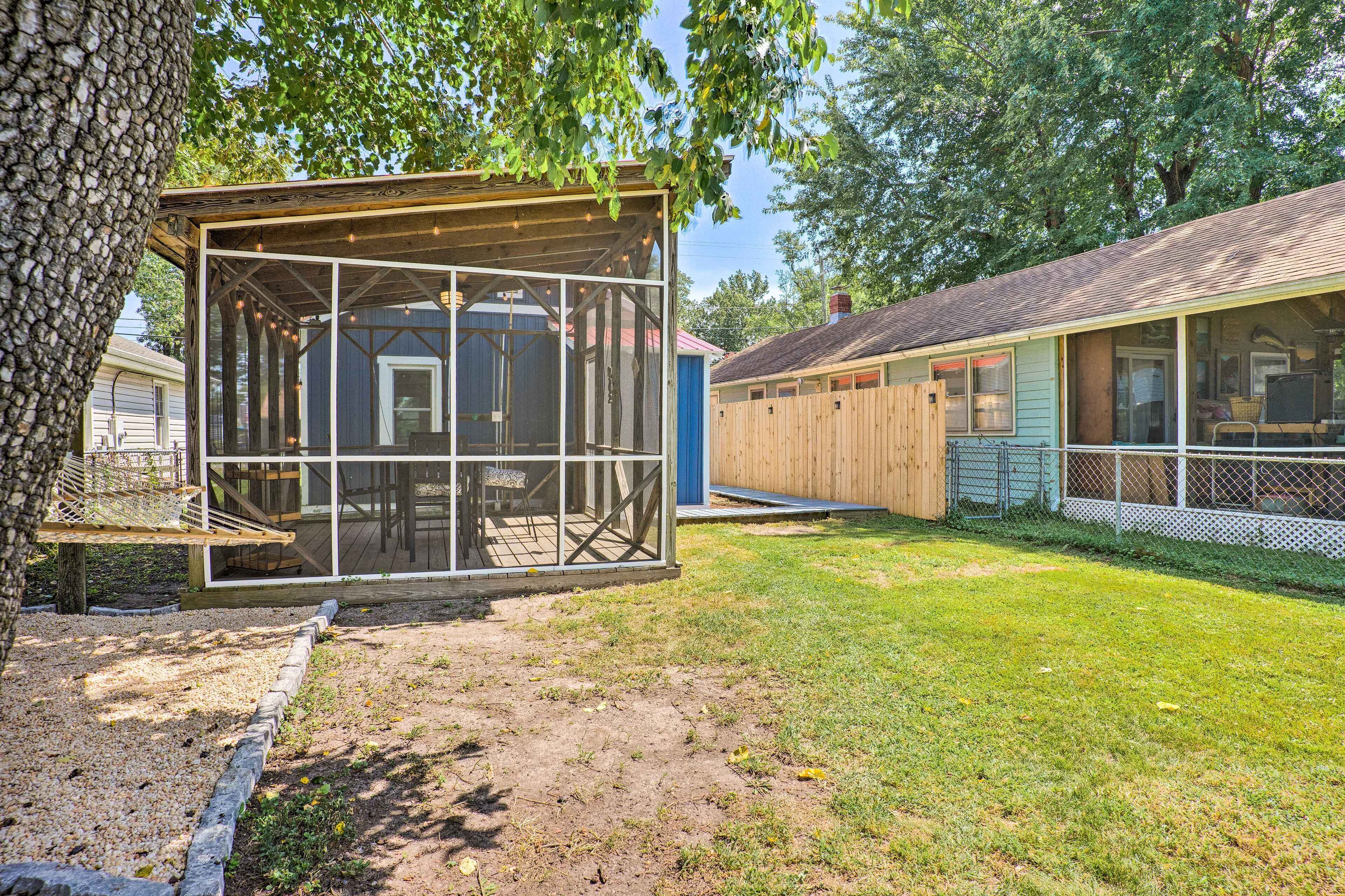 A rustic wooden structure with a screened porch, surrounded by a well-maintained lawn and trees.