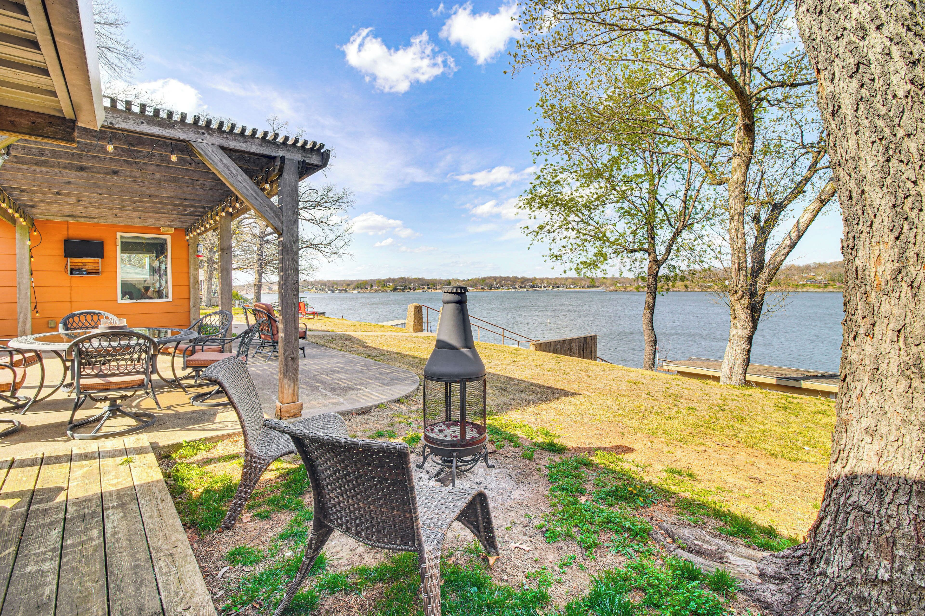 A deck with outdoor furniture, a wood-burning stove, and a view of a lake.