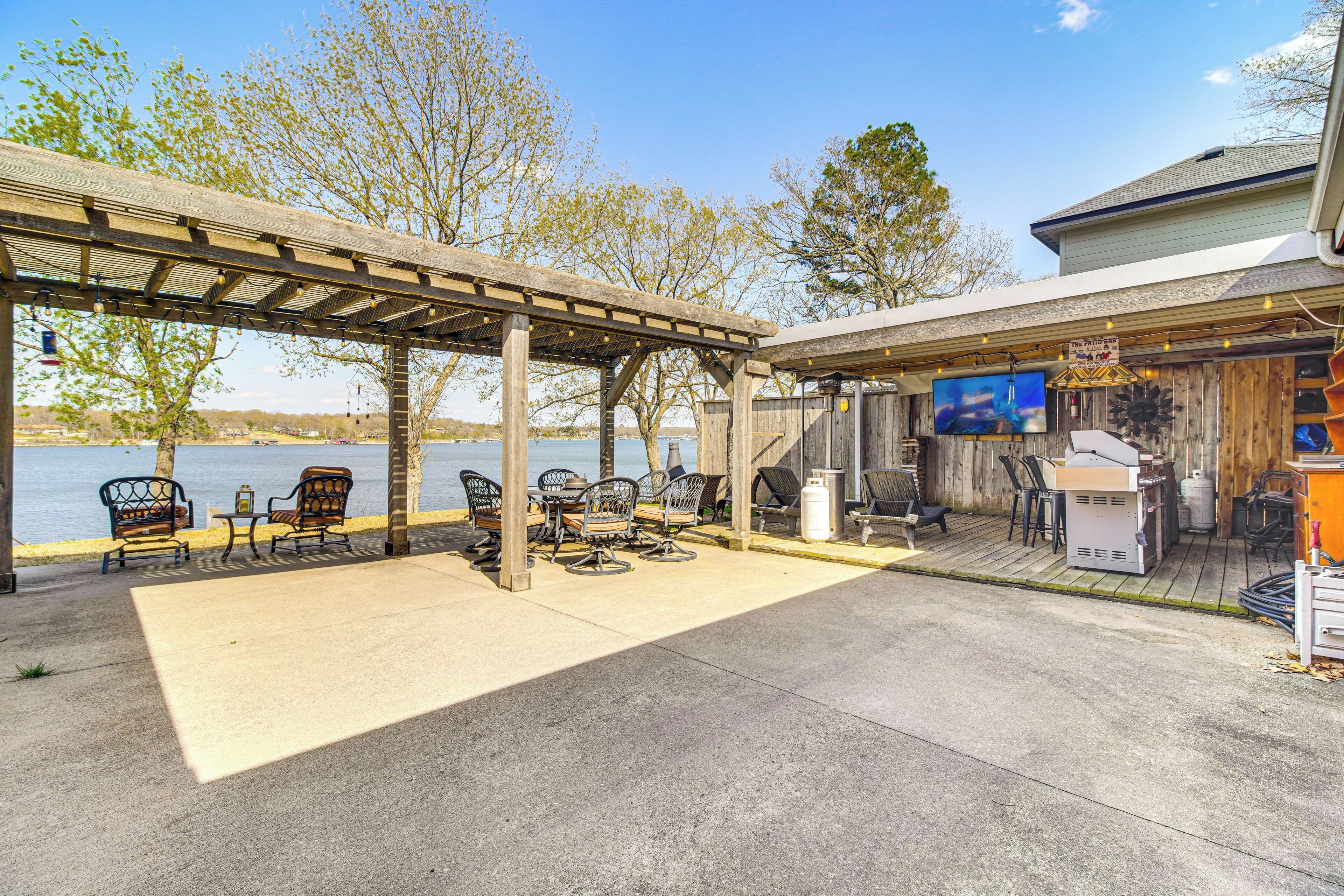 An outdoor patio with a pergola, seating area, and a bar with a TV.