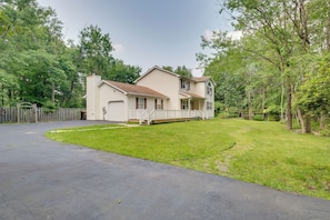 A two-story house with a front porch, a driveway, and a fenced yard.