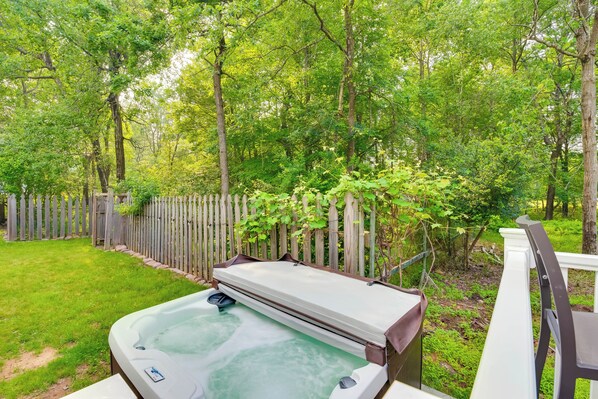 A hot tub in a backyard with a wooden fence and lush greenery.